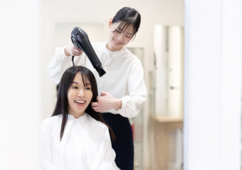 スタイリストが女性の髪をかわかしている画像